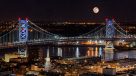view of a full moon and ben franklin bridge at night